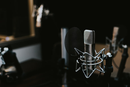 Professionelles Studiomikrofon mit Popschutz in einer dunklen, gut beleuchteten Studio-Umgebung, bereit für Podcast- oder Audioaufnahmen.