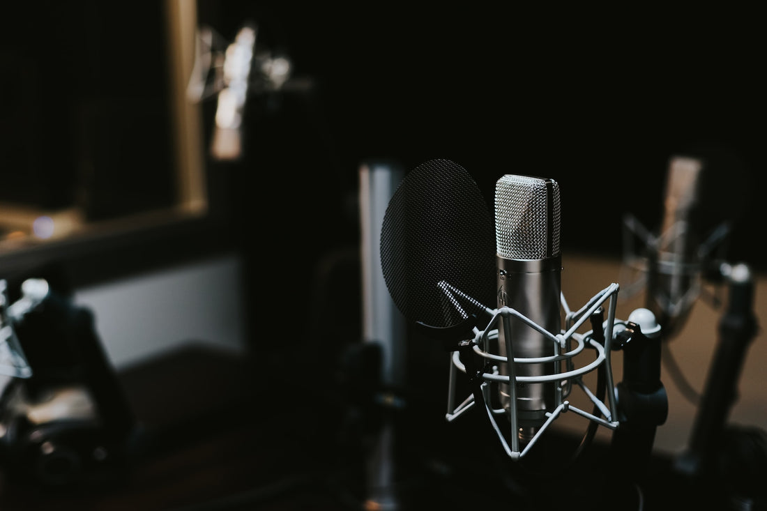 Professionelles Studiomikrofon mit Popschutz in einer dunklen, gut beleuchteten Studio-Umgebung, bereit für Podcast- oder Audioaufnahmen.